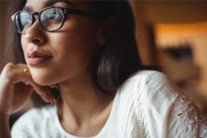 A woman with glasses gazing into the distance