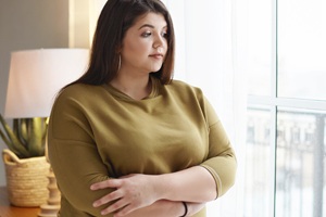 Woman standing in Livingroom with folded arms looking down